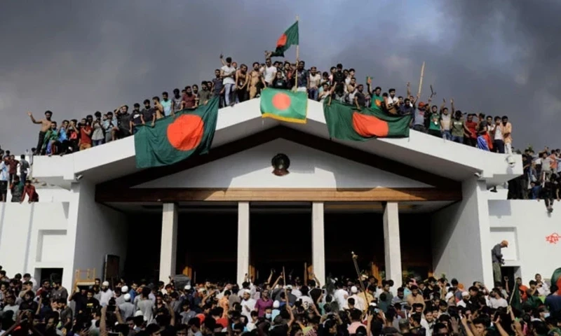 Anti-government protesters display Bangladesh´s national flag as they storm Prime Minister Sheikh Hasina’s palace in Dhaka on August 5, 2024. — AFP