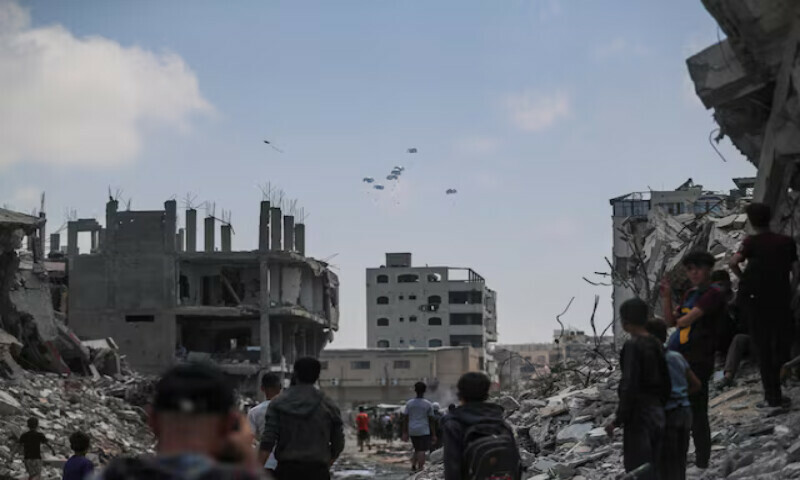 Palestinians walk as smoke rises in the distance following an Israeli strike in Khan Younis in the southern Gaza Strip. –Reuters Palestinians walk as smoke rises in the distance following an Israeli strike in Khan Younis in the southern Gaza Strip. –Reuters