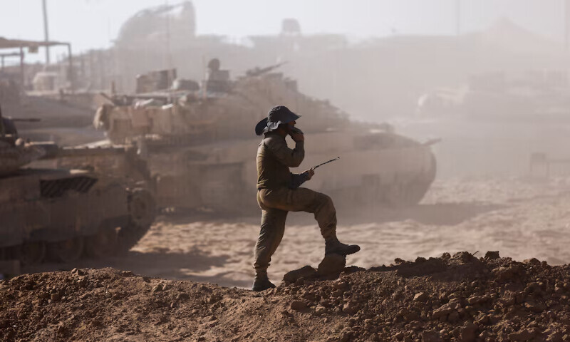 An Israeli soldier stands next to military vehicles as seen from the Israeli side of the Israel-Gaza border. – Reuters An Israeli soldier stands next to military vehicles as seen from the Israeli side of the Israel-Gaza border. – Reuters