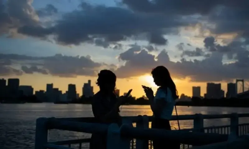 Two women using their smartphones in Japan. Photo via AFP Two women using their smartphones in Japan. Photo via AFP