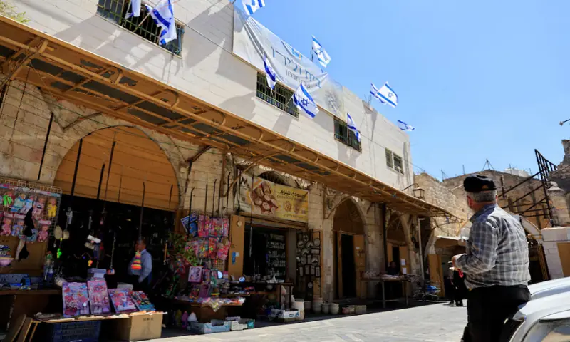 A Palestinian looks at Israeli flags placed over a house which was taken over by Israeli settlers in the old city, in Hebron, in the Israeli-occupied West Bank on September 3, 2025. Reuters
