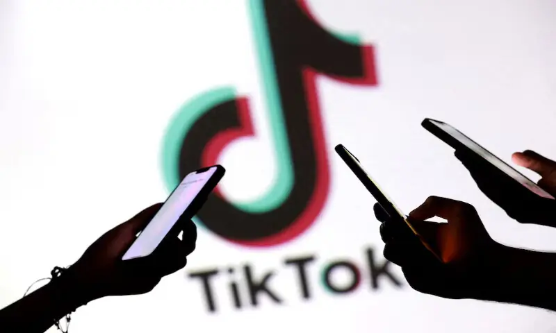 Teenagers pose for a photo while holding smartphones in front of a TikTok logo in this illustration. – Reuters Teenagers pose for a photo while holding smartphones in front of a TikTok logo in this illustration. – Reuters