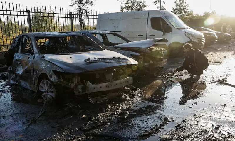 A police officer works near damaged vehicles at the site of a residential building damaged during a Russian drone and missile strike on the outskirts of Kyiv, Ukraine. – Reuters