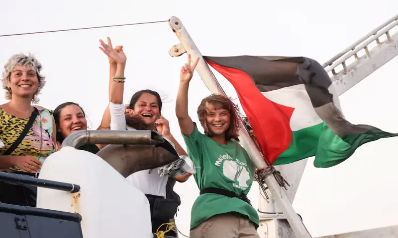 Greta Thunberg and a crew member flash victory signs from their boat, as they sail off Crete island, Greece. – Reuters