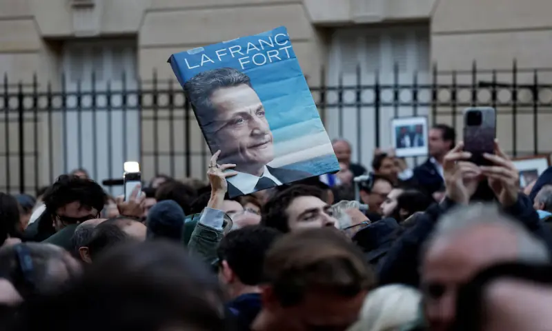 [1/3] A supporter holds a poster with a portrait of Nicolas Sarkozy and the slogan “Strong France” as people attend a gathering called by the sons of former French President Nicolas Sarkozy in support of their father on the day he begins his five-year prison sentence at the Sante prison for criminal conspiracy over attempts to raise campaign funds from Libya, in Paris, France, October 21, 2025.//reuters