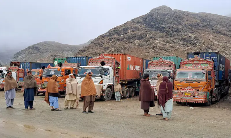 People stand next to parked trucks loaded with supplies at the Torkham border crossing. – Reuters file