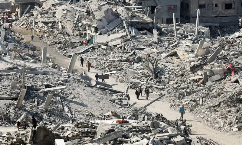 Palestinians walk past the rubble of destroyed buildings in Gaza City on Sunday. – Reuters