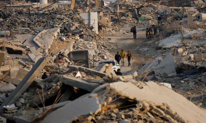 Palestinians walk past the rubble of destroyed buildings in Jabalia, northern Gaza Strip. – Reuters
