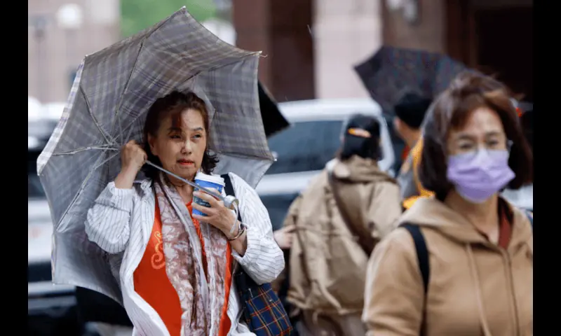 A woman holds her umbrella amidst strong winds and rain as Typhoon Fung-wong approaches, in Taipei, Taiwan, November 11, 2025//REUTERS