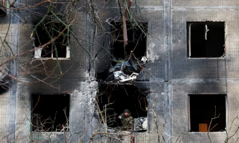 An investigator looks through the window of an apartment building damaged during an overnight Russian drone and missile strike, amid Russia’s attack on Ukraine, in Kyiv, on November 14, 2025. Reuters
