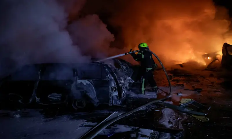 A firefighter puts out burning cars near the apartment building hit by a Russian drone strike, amid Russia’s attack on Ukraine, in Kharkiv, Ukraine, November 19, 2025//REUTERS A firefighter puts out burning cars near the apartment building hit by a Russian drone strike, amid Russia’s attack on Ukraine, in Kharkiv, Ukraine, November 19, 2025//REUTERS