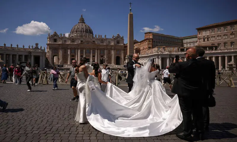 A groom arranges the wedding dress of the bride during their wedding photo session on St. Peter’s Square at the Vatican. – Reuters file