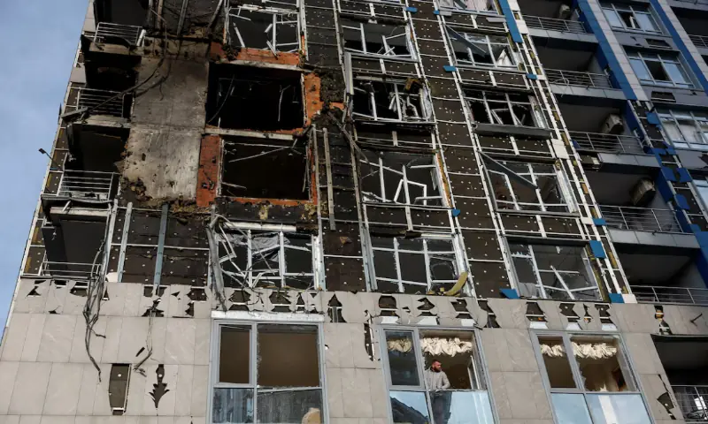 A resident looks through a broken window of an apartment building hit by a Russian drone strike, amid Russia’s attack on Ukraine, in Kyiv, Ukraine, November 25, 2025//REUTERS