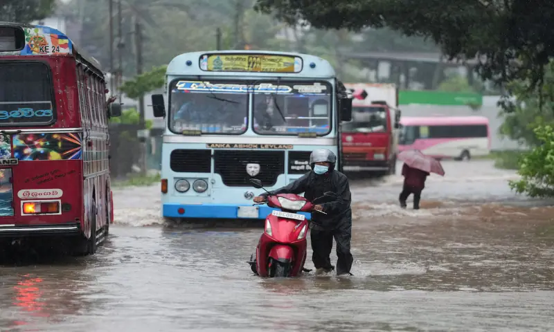 People and vehicles wade through a waterlogged street following heavy rainfall in Kelaniya, Sri Lanka, November 28, 2025//REUTERS