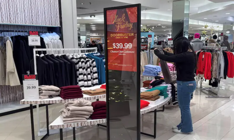 An employee folds clothes at a Macy’s department store during Black Friday deals at the Roosevelt Field mall in Garden City, New York. – Reuters