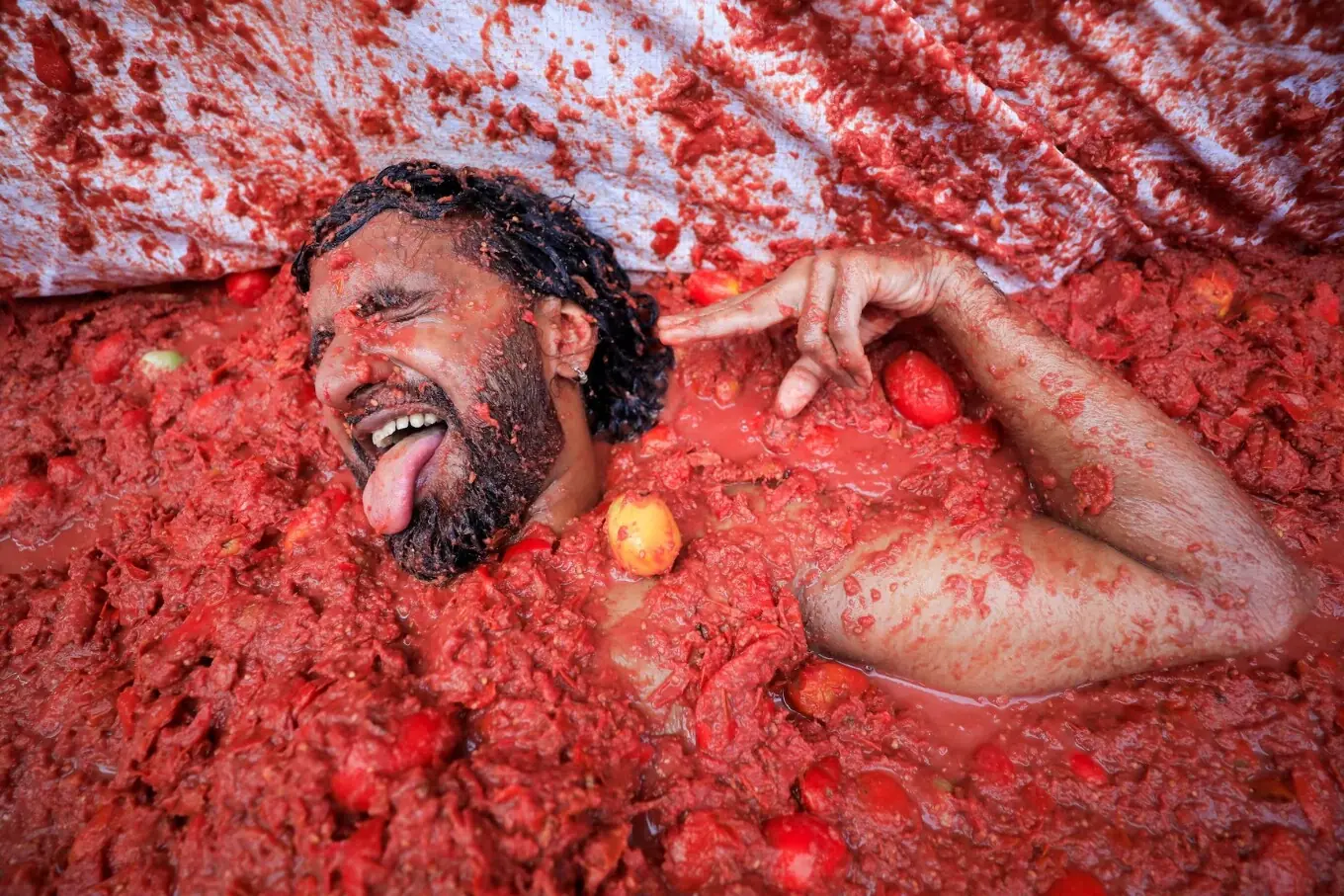 اسپین کے شہر والنسیا کے قریبی قصبے بونول میں 27 اگست کو سالانہ ’لا ٹوماتینا‘ فوڈ فائیٹ فیسٹیول میں شریک ایک شخص ٹماٹروں کے رس میں لیٹے ہوئے ہاتھ ہلا کر خوشی کا اظہار کر رہا ہے۔ اسپین کے شہر والنسیا کے قریبی قصبے بونول میں 27 اگست کو سالانہ ’لا ٹوماتینا‘ فوڈ فائیٹ فیسٹیول میں شریک ایک شخص ٹماٹروں کے رس میں لیٹے ہوئے ہاتھ ہلا کر خوشی کا اظہار کر رہا ہے۔