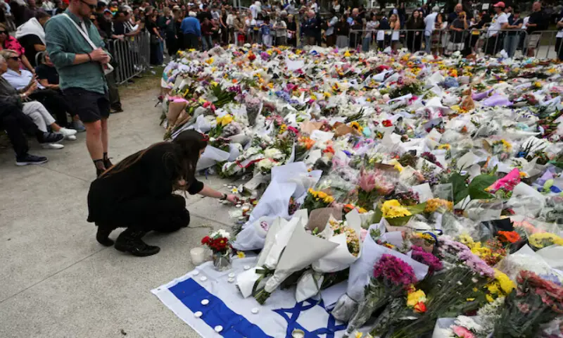 A woman places a candle next to flowers laid as a tribute for the Bondi Beach attack victims in Sydney, Australia. &ndash; Reuters