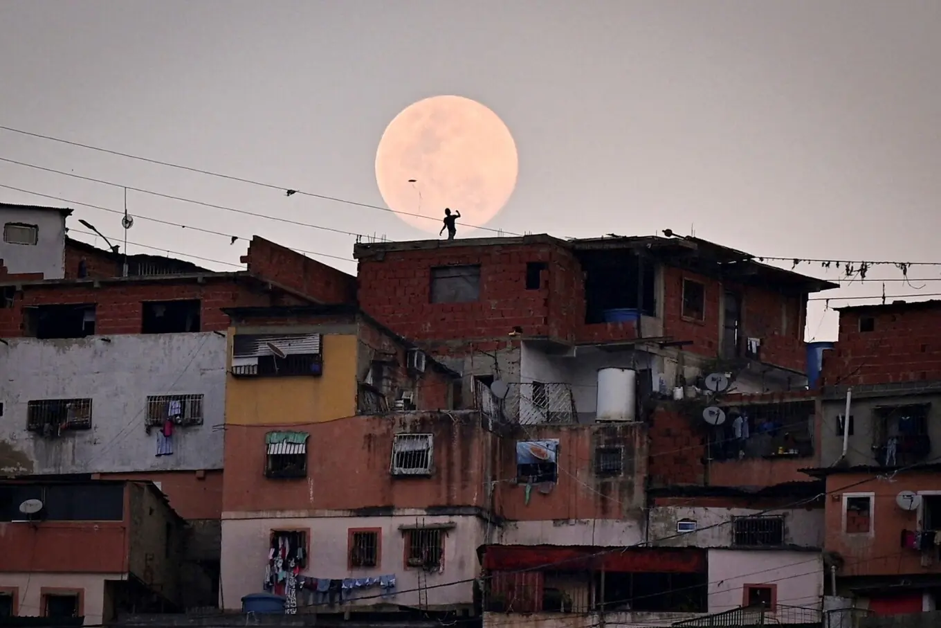 12 مارچ 2025 کو کیریکاس، وینزویلا کے پیٹارے علاقے میں چاند نکلتے وقت ایک بچہ پتنگ اڑا رہا ہے