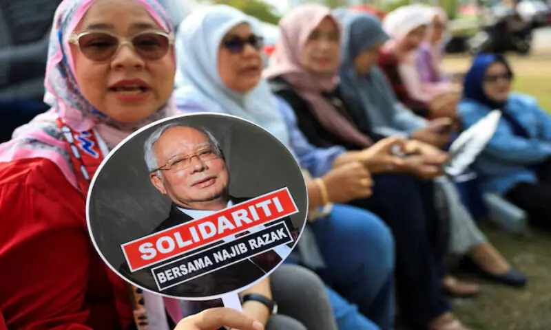 A supporter of former Malaysian prime minister Najib Razak holds a hand fan with a picture of Najib printed on it, outside the Malaysian federal court at Putrajaya, Malaysia. &ndash; Reuters file
