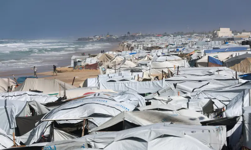 Displaced Palestinians walk at a beach tent camp, after it was flooded by rising seawater during a winter storm in Khan Younis, southern Gaza Strip. &ndash; Reuters
