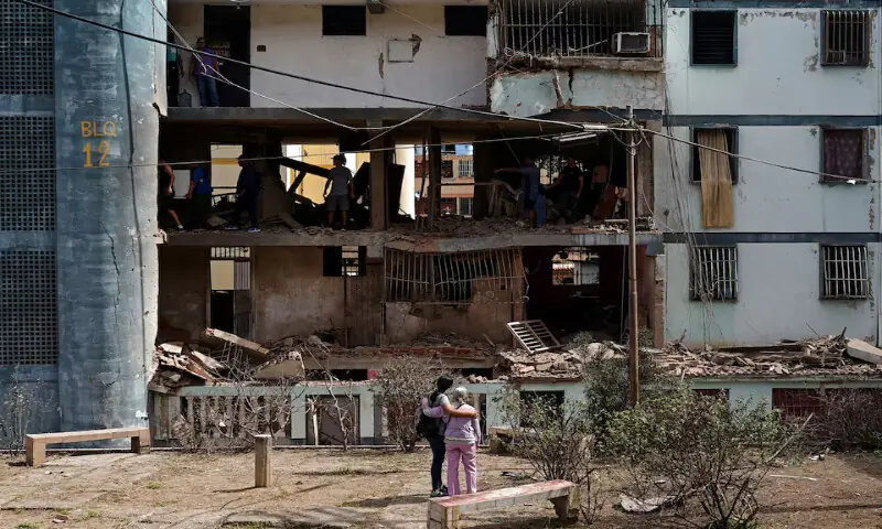 Women look at a damaged building as people inspect the rubble inside it following US strikes on Venezuela in Catia La Mar, Venezuela. &ndash; Reuters