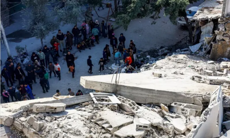 Palestinians at the site of a collapsed house that was damaged during the war by an Israeli strike, in the central Gaza Strip, on January 5, 2026. Reuters