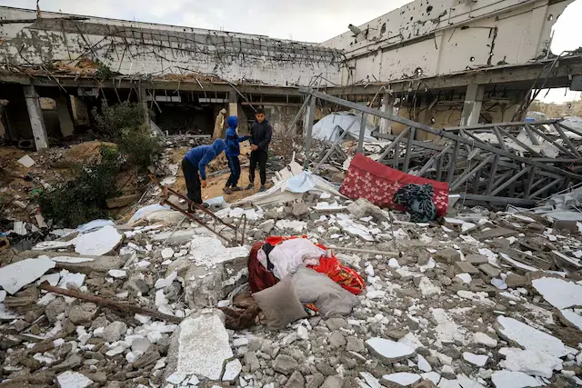 Palestinians inspect the damage at the site of a war-damaged building after parts of it collapsed, on a windy winter day, in Gaza City. &ndash; Reuters