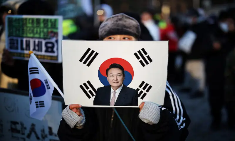A woman holds a sign bearing the South Korean national flag with a portrait of former president Yoon Suk Yeol at a court in Seoul, South Korea. &ndash; Reuters