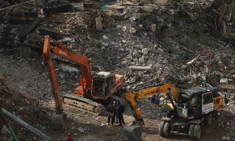 An emergency worker and police officers speak during a break following a massive fire that broke out in the Gul Plaza Shopping Mall in Karachi. – Reuters An emergency worker and police officers speak during a break following a massive fire that broke out in the Gul Plaza Shopping Mall in Karachi. – Reuters