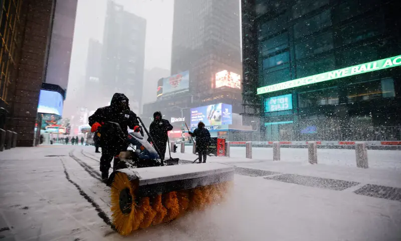 Workers remove snow from the sidewalk during snowfall around Times Square in New York City, US. &ndash; Reuters