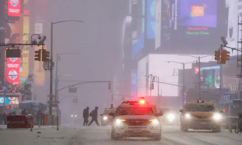 People cross the street during snowfall at Times Square in New York City, US. &ndash; Reuters