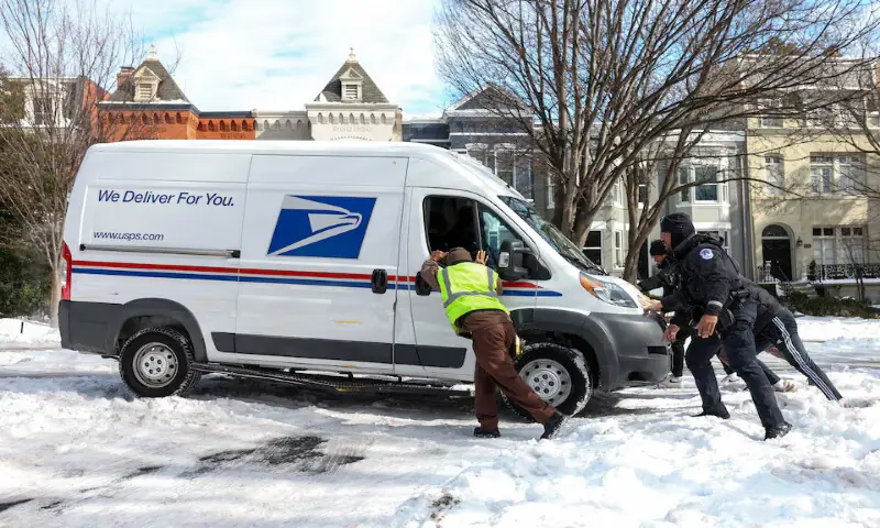 People help push a United States Postal Service truck out of snow and ice in Washington, DC. &ndash; Reuters