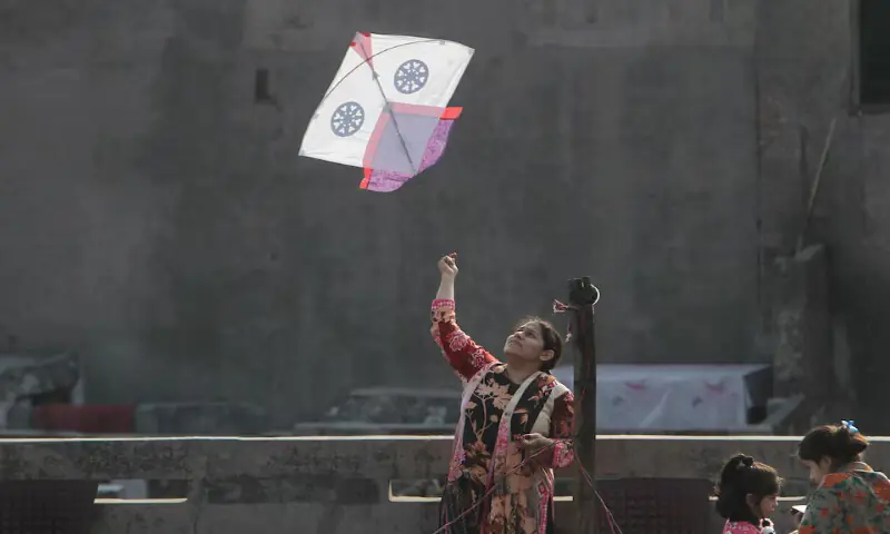 A woman flies a kite from a rooftop to mark Basant in Lahore. &ndash; Reuters