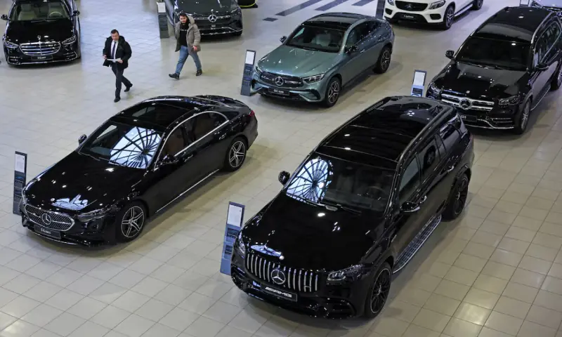 An employee and a visitor walk past Mercedes-Benz cars at a Panavto dealership in Moscow, Russia. &ndash; Reuters