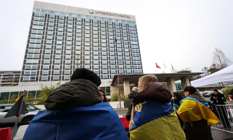 People wrapped in Ukrainian flags stand outside the InterContinental hotel on the day of peace talks between Russia and Ukraine in Geneva, Switzerland. &ndash; Reuters