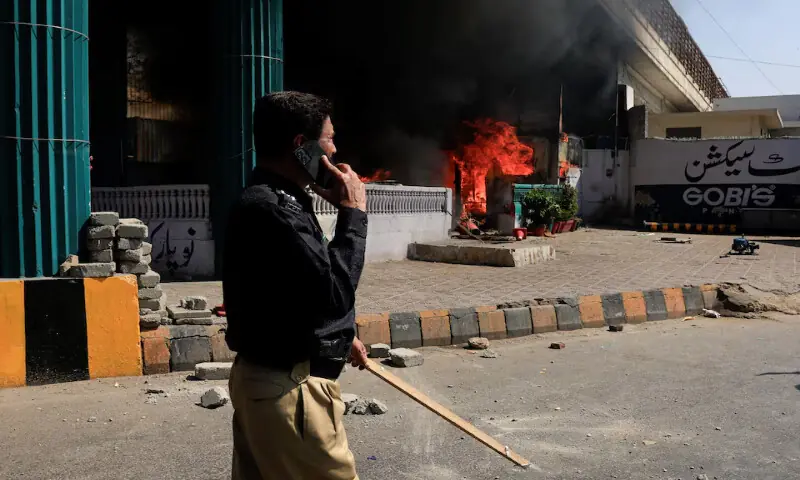A police officer walks next to a checkpost set ablaze in a protest outside the US Consulate General in Karachi on Sunday. – Reuters A police officer walks next to a checkpost set ablaze in a protest outside the US Consulate General in Karachi on Sunday. – Reuters