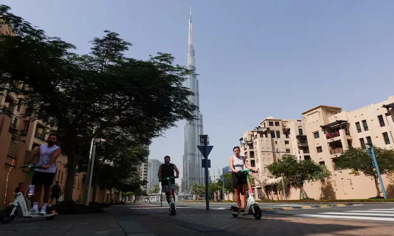 People ride scooters on a street with Burj Khalifa in the background after an Iranian attack in Dubai. – Reuters People ride scooters on a street with Burj Khalifa in the background after an Iranian attack in Dubai. – Reuters