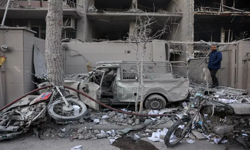A man stands next to damaged vehicles in the aftermath of an Israeli and the US strike on a police station in Tehran, Iran. &ndash; Reuters