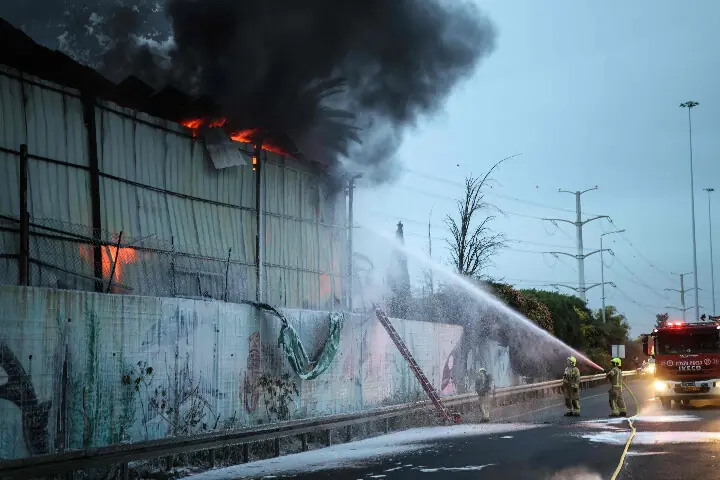 Firefighters extinguish a fire at the site of a strike on the outskirts of Tel Aviv on March 13, 2026. AFP