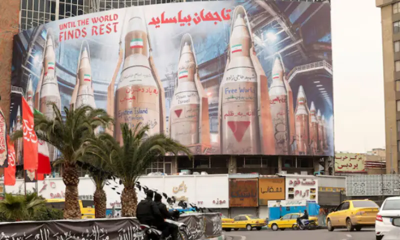 People on motorcycles ride past a large billboard with images of Iranian missiles, amid the U.S.-Israeli conflict with Iran, in Tehran, Iran. &ndash; Reuters