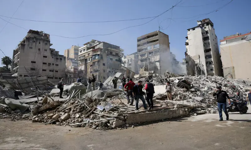 People walk amidst debris at the site of an Israeli strike in the Zuqaq Al Blat district in central Beirut, Lebanon. &ndash; Reuters
