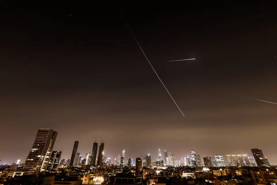 Streaks of light and a flying aircraft illuminate the sky during an interception attempt amid the U.S.-Israeli conflict with Iran, as seen from Tel Aviv, Israel. &ndash; Reuters
