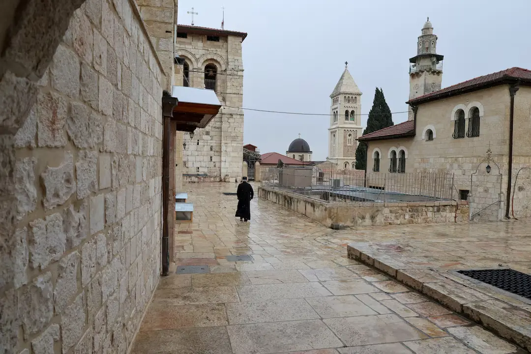 A person walks near the Church of the Holy Sepulchre as it is locked following the cancellation of the traditional Palm Sunday procession from the Mount of Olives, amid restrictions on gathering in large groups and the U.S.-Israel conflict with Iran, in Jerusalem&rsquo;s Old City. &ndash; Reuters