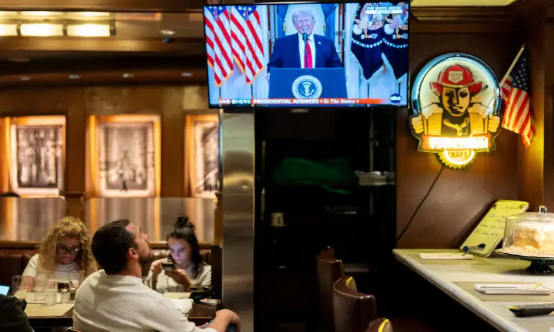 A customer watches US President Donald Trump address to the nation on screen at Brooklyn Diner in Times Square, New York. &ndash; Reuters
