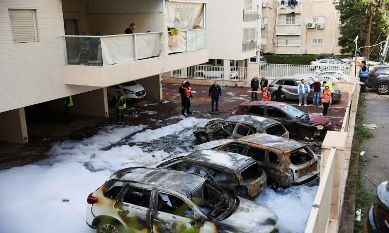 Emergency personnel work next to burnt-out vehicles at an impact site following a barrage of missiles launched from Iran in Petach Tikva, Israel, on Monday. &ndash; Reuters