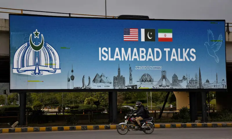 A man rides his motorbike past a billboard installed alongside a road as Islamabad prepares to host the US and Iran for peace talks. &ndash; Reuters