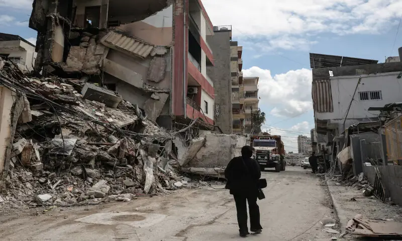 A woman walks past buildings destroyed during Israeli strikes in Tyre, Lebanon. &ndash; Reuters