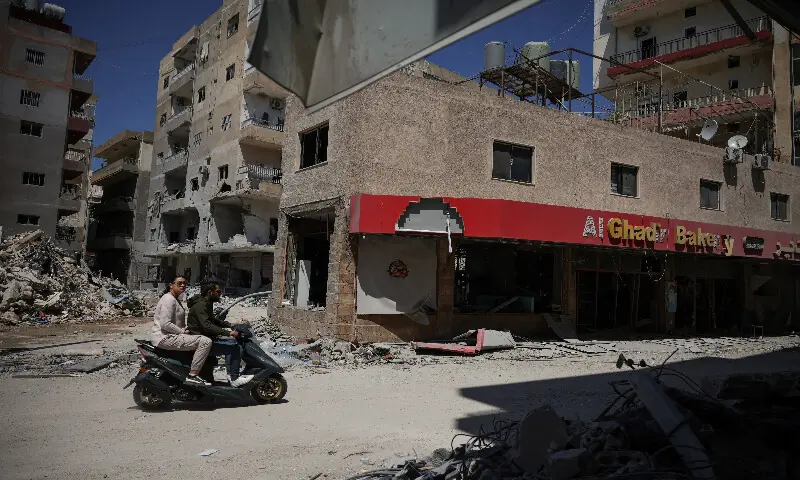 A couple rides a scooter through an area damaged during Israeli strikes in Tyre, south Lebanon. – Reuters A couple rides a scooter through an area damaged during Israeli strikes in Tyre, south Lebanon. – Reuters