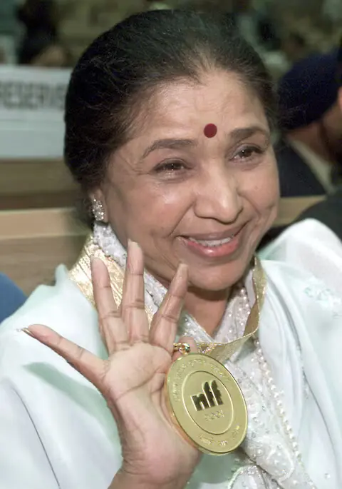 Indian singer Asha Bhosle holds aloft a Dada Saheb Phalke award in New Delhi. &ndash; Reuters