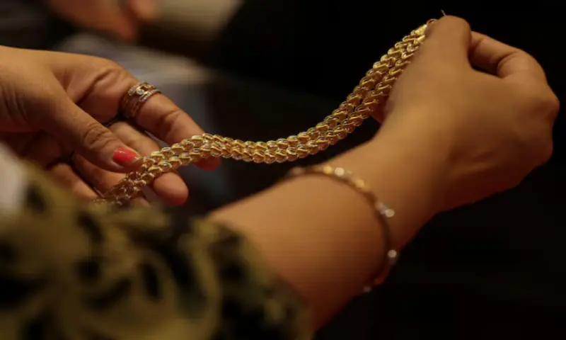 A customer holds a gold chain at a jewellery store in Mumbai, India. &ndash; Reuters